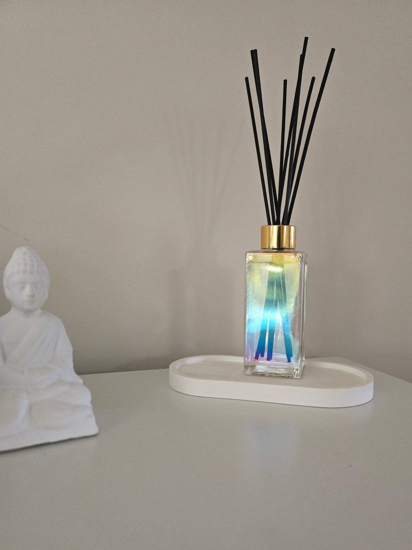 Diffuser with black sticks on a white stand against a beige wall.