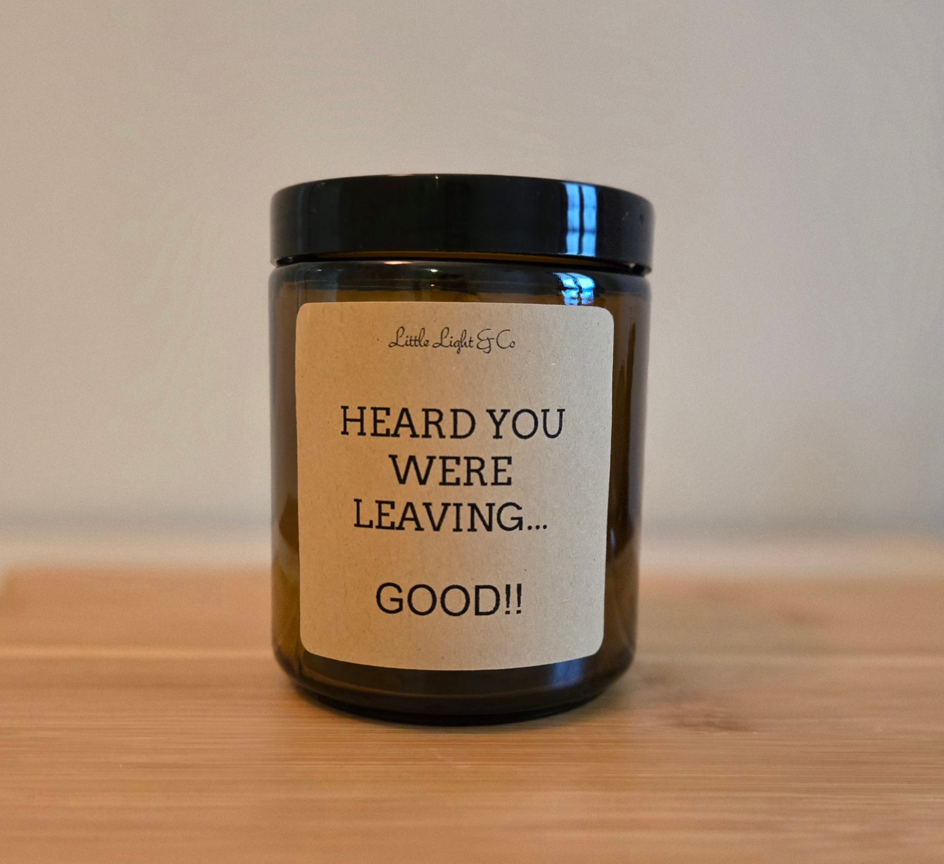 Candle jar with a humorous label on a wooden surface