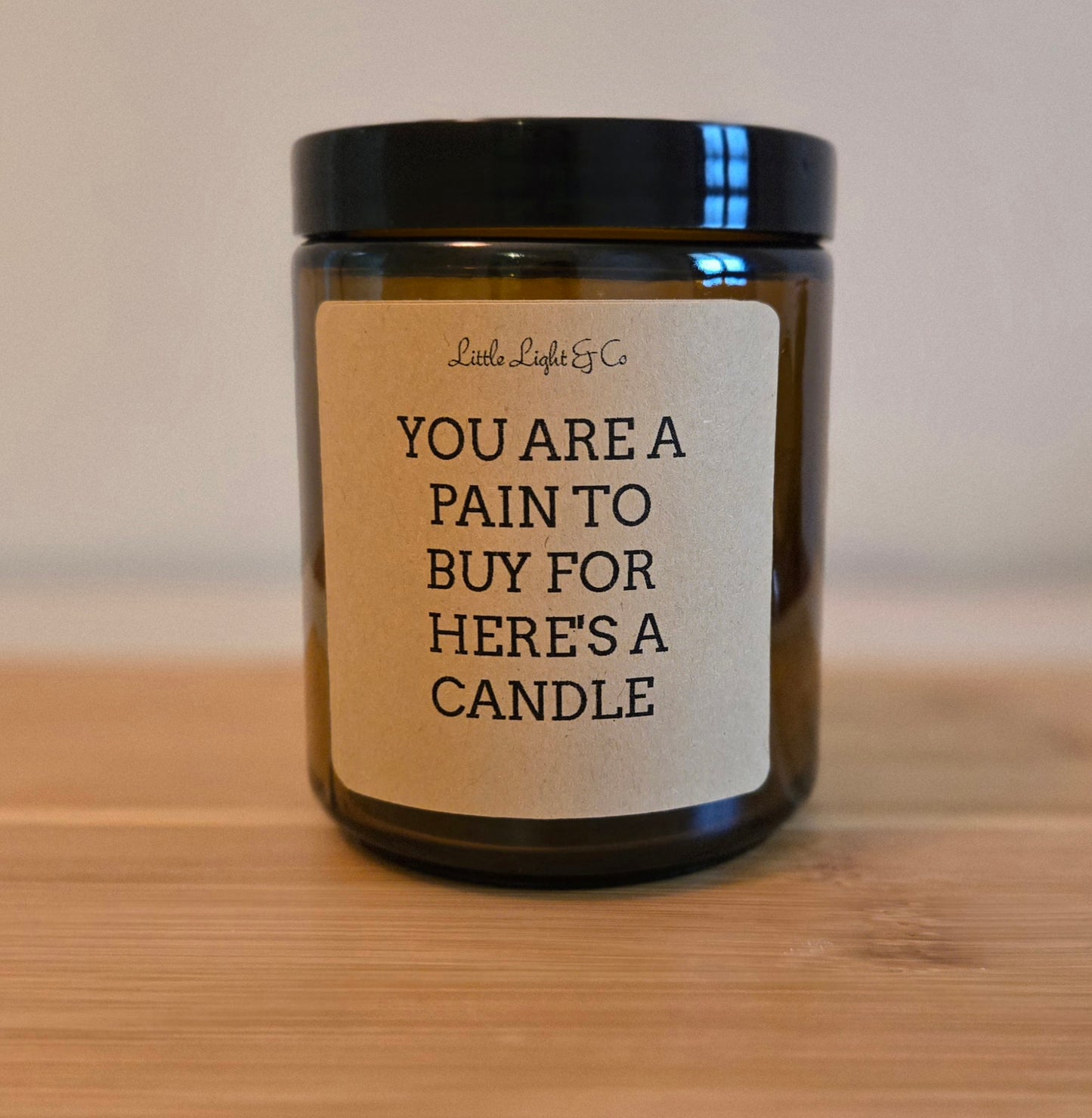 Candle with a humorous label on a wooden surface