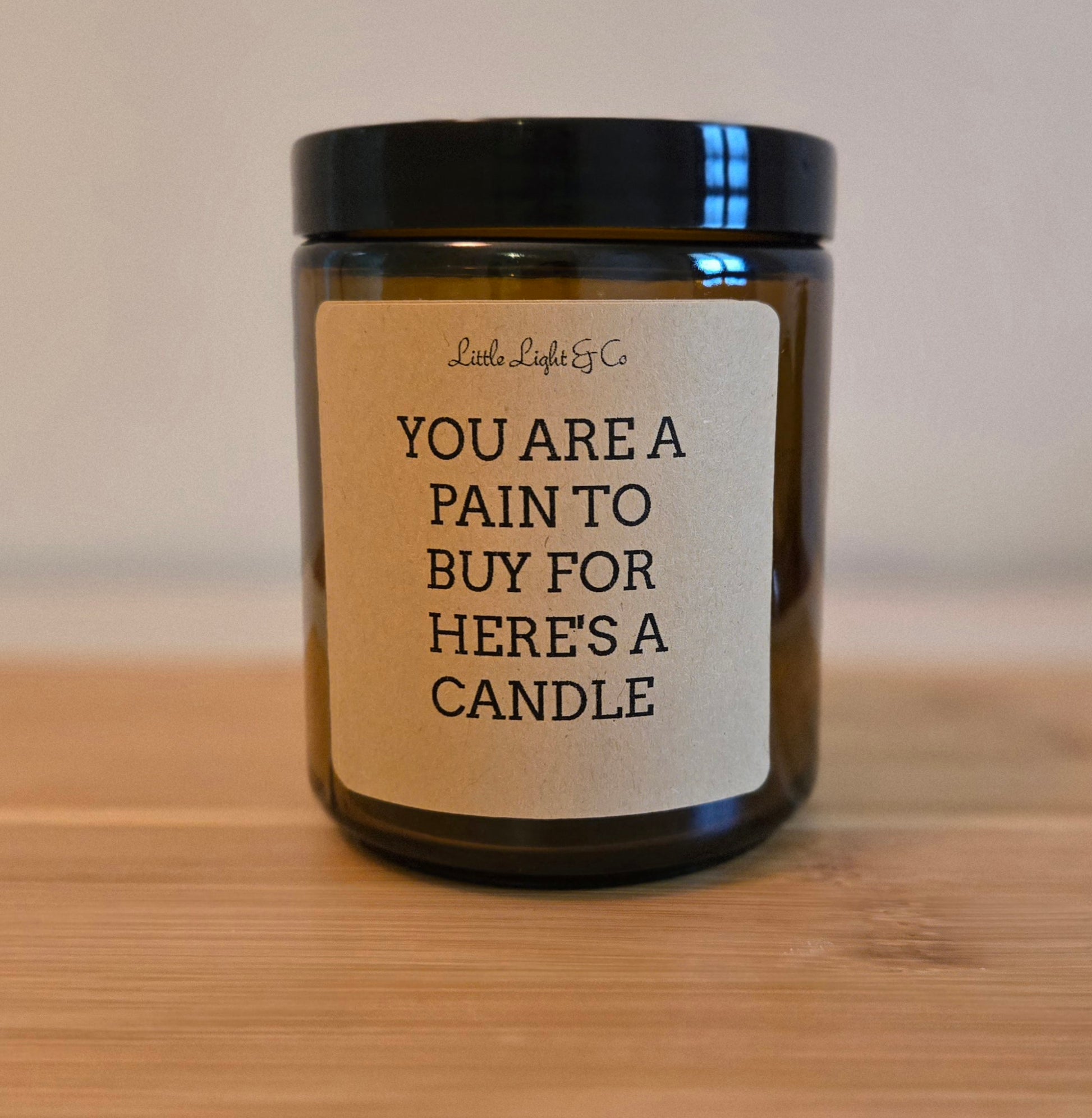 Candle with a humorous label on a wooden surface