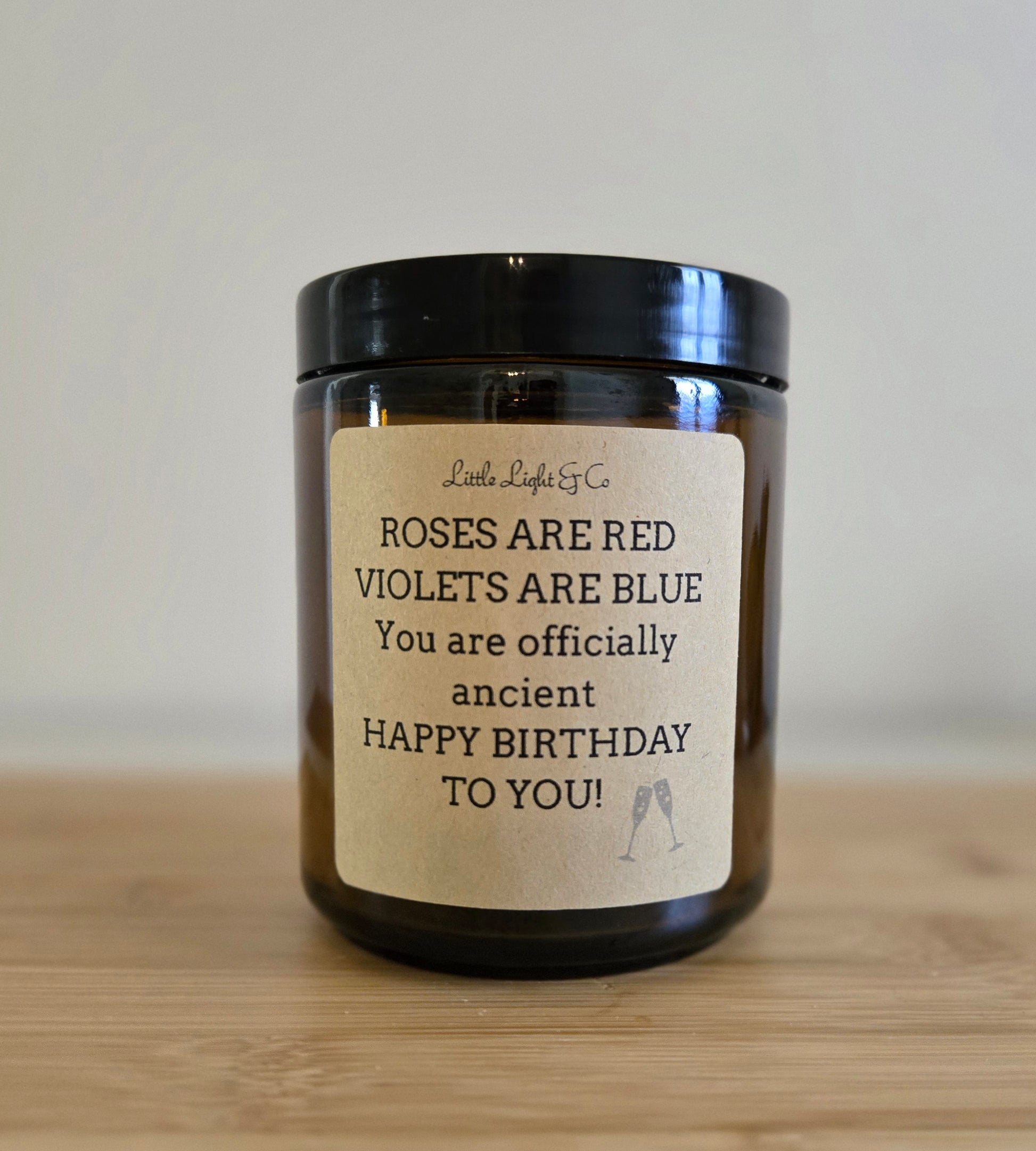 Candle with a birthday message label on a wooden surface