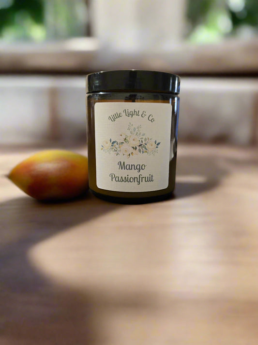 Jar of 'Mango Passionfruit' candle with a label on a textured surface.