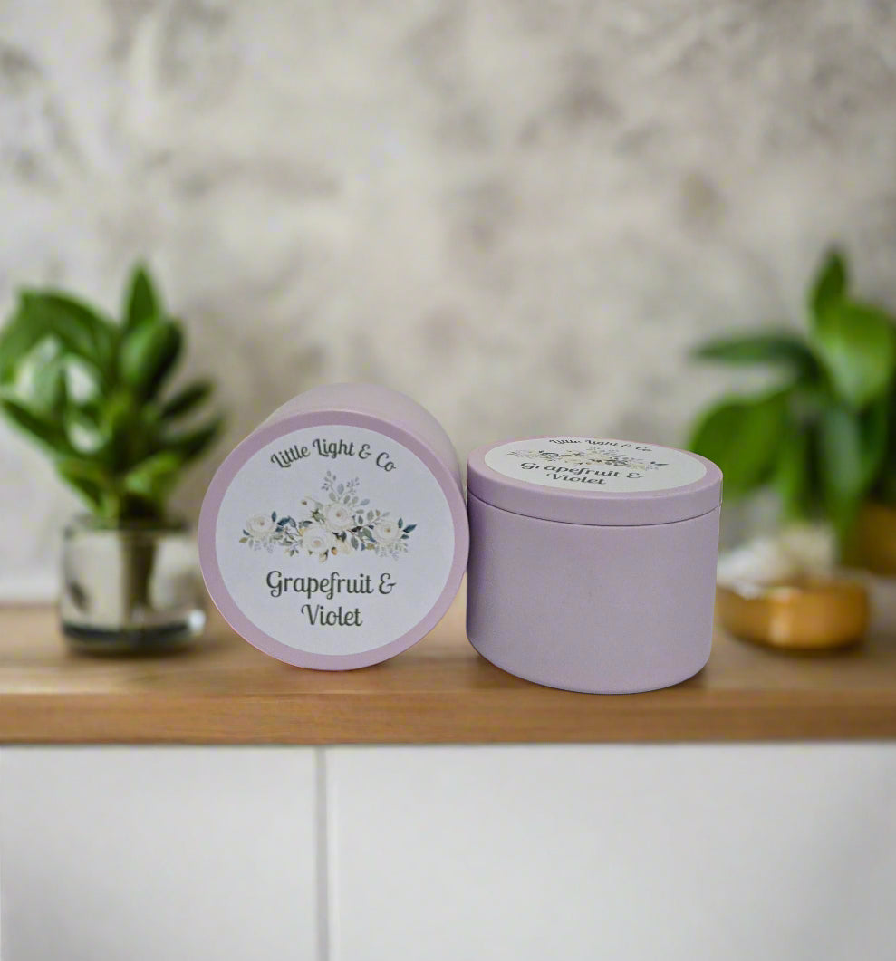 Purple candle tin with 'Grapefruit & Violet' fragrance on a white background