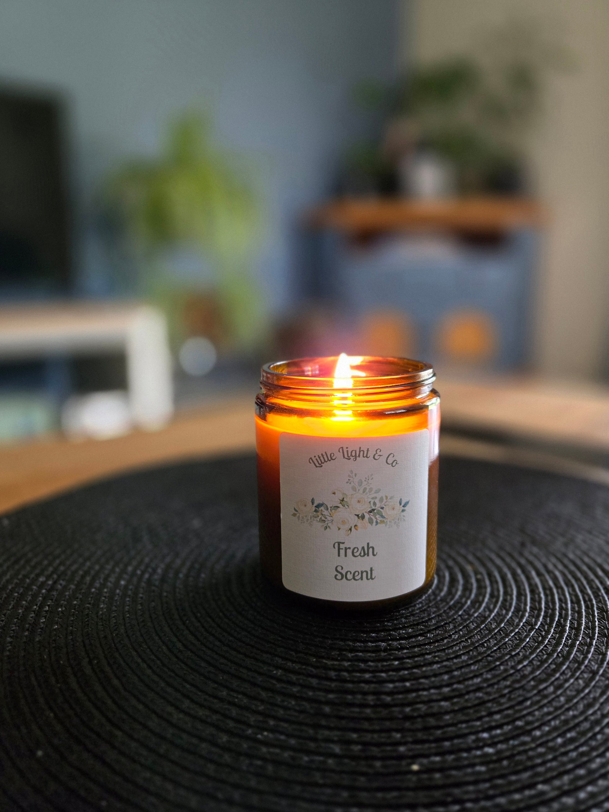 Candle in a jar labeled 'Fresh Scent' glowing lit candle