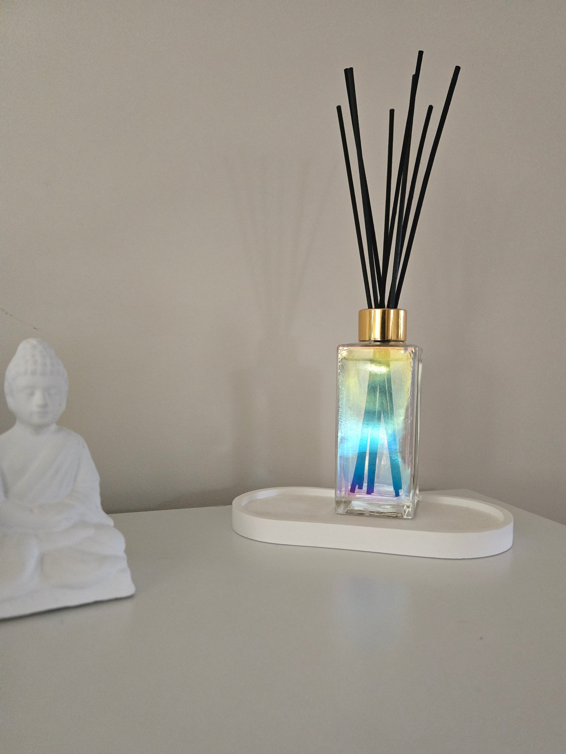 Diffuser with black sticks on a white stand against a beige wall.