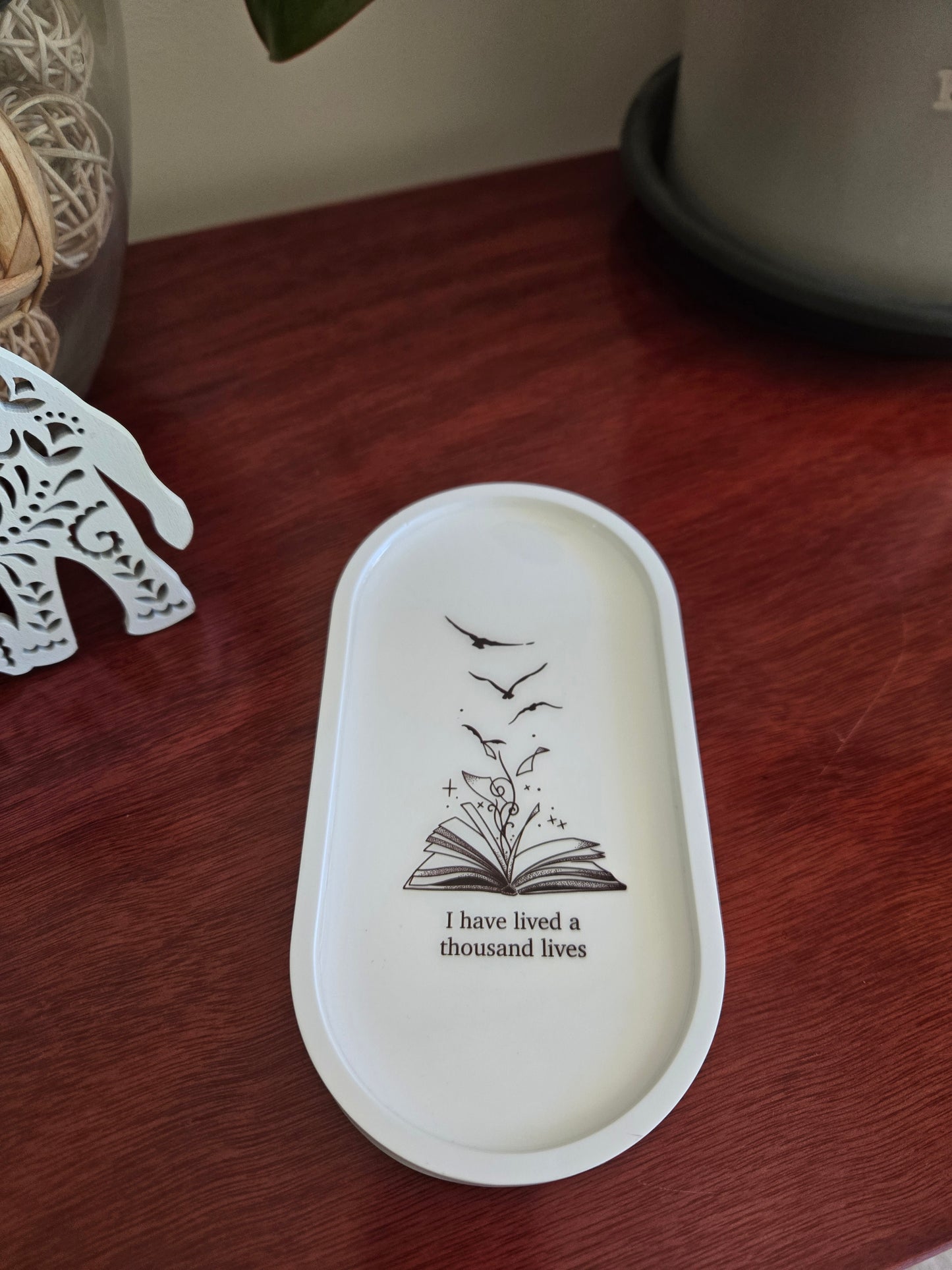 White decorative tray with black design and text on a wooden surface